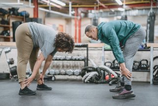 Two people stretching in a gym